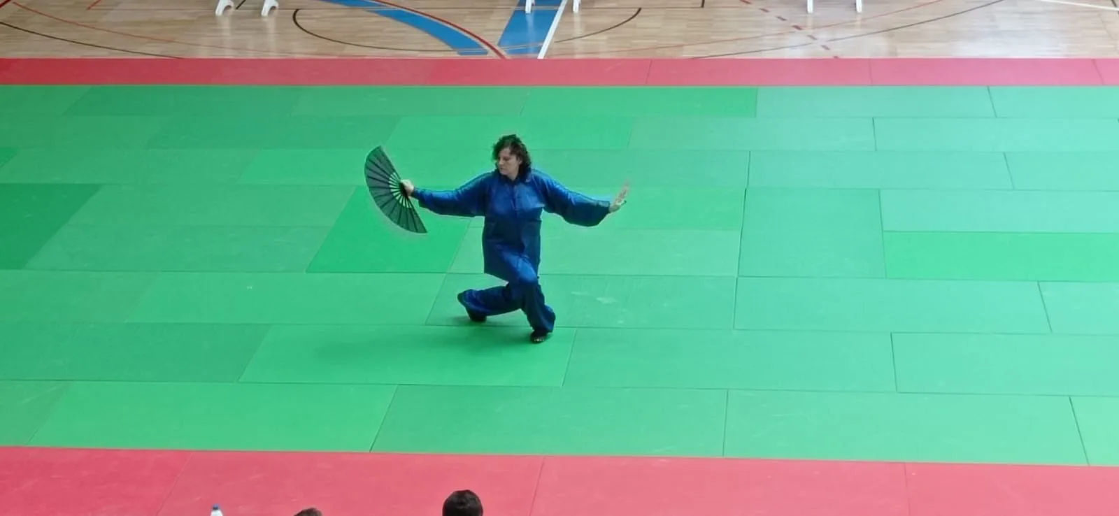 Maite García en competición de wushu con abanico verde